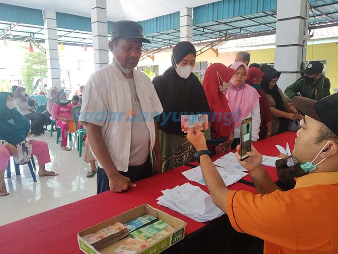 ILUSTRASI Petugas dari PT Pos Indonesia (Persero) mengecek wajah penerima bantuan di kantor Desa Rogojampi, Banyuwangi beberapa waktu lalu.