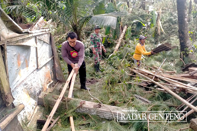 KERJA BAKTI: Anggota TNI, kepolisian, dan warga gotong royong mengevakuasi pohon tumbang yang menimpa rumah warga, Jumat (16/12). (ISMANTO UNTUK JPRG)