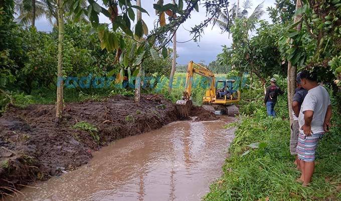 NORMALISASI: sungai kecil yang mengalir dari Perkebunan Kalikempit, PTPN XII Desa Tulungrejo, Kecamatan Glenmore, dikeruk menggunakan alat berat, Kamis (22/12). (Ismanto untuk RadarBanyuwangi.id)