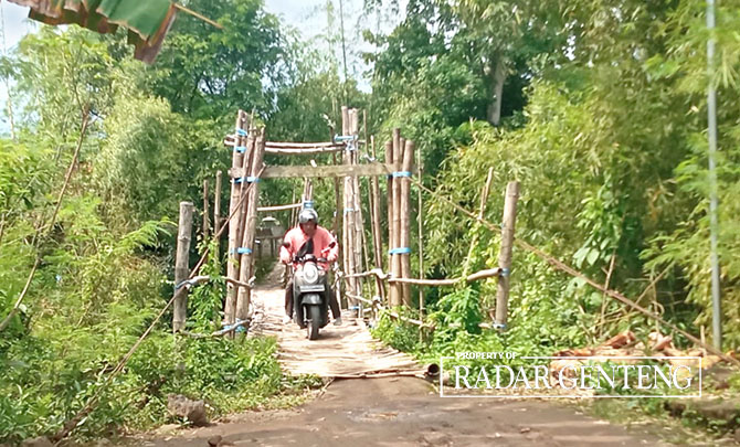 HATI-HATI: Pemotor melintas jembatan gantung Mbok Kayah yang menghubungkan Dusun Bayatrejo, Desa Wringinpitu, Kecamatan Tegaldlimo dengan Dusun Rumping, Desa Plampangrejo, Kecamatan Cluring, Jumat (20/1). (Lugas Rumpakaadi/Radar Genteng)