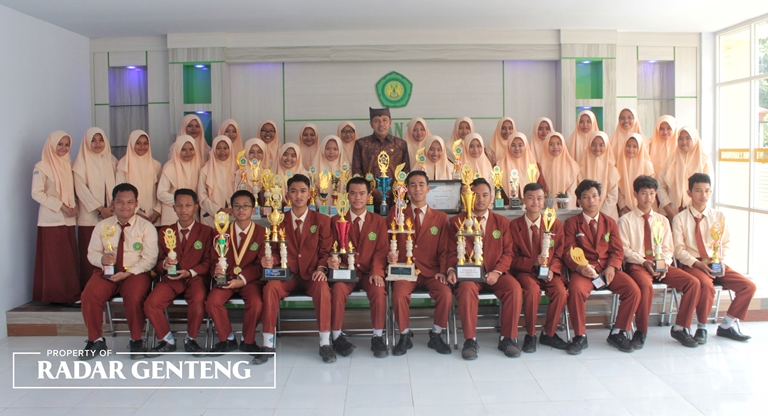 PENUH PRESTASI: Kepala MAN 2 Banyuwangi Drs H Saeroji, M.Ag (tengah) bersama para siswa berprestasi dengan piala yang diraih, Senin (2/1). (Salis Ali/JPRG).