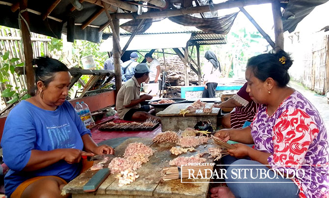KEJAR TARGET: Sejumlah warga Dusun Barat Kebun, Desa Wringinanom, Kecamatan Panarukan, sibuk menusuk daging ayam di depan rumahnya, Sabtu (7/1). (Humaidi/Radar Situbondo)