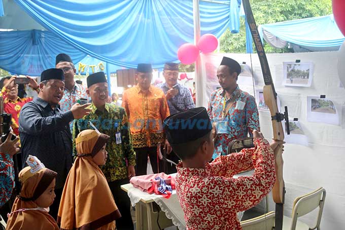 UNJUK PRESTASI: Ketua Yayasan Al Uswah Karyono menunjukkan keahlian siswa SDIT Al Uswah 2 saat memanah kepada Kabid SD Dispendik Sutikno. (Al Uswah 2 Untuk RadarBanyuwangi.id)