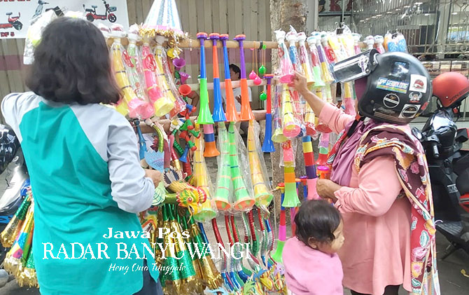 PILIH WARNA: Lilik Sugiarti (kiri) ketika memilihkan terompet untuk pembeli di Jalan Satsuit Tubun, Banyuwangi, Minggu (1/1/23). (Gareta Wardani/Radar Banyuwangi)