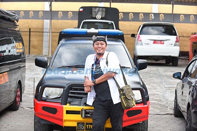 PAKAI UDENG: Ivan berdiri di mobil polisi saat liputan Festival Tradisi Islam Nusantara di Stadion Diponegoro, Senin (9/1).  (Ramada Kusuma/RadarBanyuwangi.id)