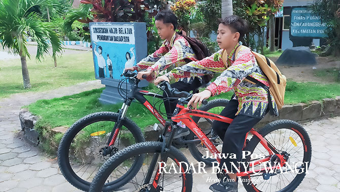 PULANG SEKOLAH: Muhamad Dian Septiawan (kanan) dan Aditya Fitra Maulana mengayuh sepeda pemberian Presiden Jokowi, Rabu (11/1).(Dedy Jumhardiyanto/Radar Banyuwangi)