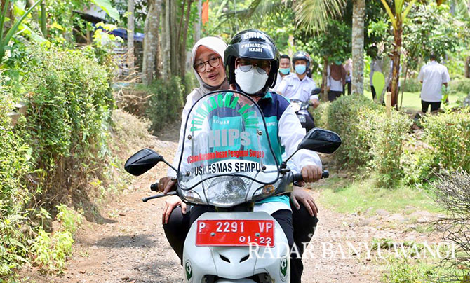 BERI LAYANAN KESEHATAN: Alfi Hidayati memboncengkan Bupati Ipuk Fiestiandani menyusuri jalan di pelosok Desa Jambewangi, Kecamatan Sempu. (DINI UNTUK RABA)
