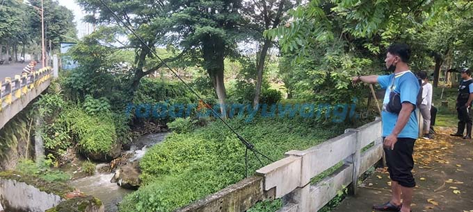 DIKENAL ANGKER: Iwan Budi Astawa menunjukkan bekas pohon bendo yang tumbuh di sungai yang diapit kuburan milik Kampung Melayu dan Pengantigan. (Syaifuddin Mahmud/RadarBanyuwangi.id)