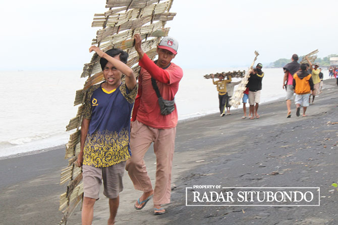 GOTONG PAGAR: Warga membongkar paksa anyaman bambu yang dipakai untuk pagar pembatas lokasi pembangunan tambak di Desa Tanjung Kamal, Kecamatan Mangaran, Situbondo, Sabtu (5/2). (Iwan Feriyanto/Radar Situbondo)
