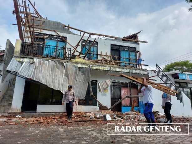 PEMBERSIHAN PUING: Sejumlah pekerja bersama anggota POlsek Songgon membersihkan puing-puing bangunan yang roboh di barat Pendapa Kantor Camat Songgon, Kamis pagi (23/2). (Foto: Lugas Rumpakaadi/JPRG)