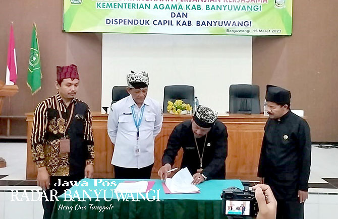 PERMUDAH LAYANAN: Moh. Amak Burhanudin menandatangani surat kerja sama didampingi Djuang Pribadi (baju putih) di kantor Kemenag Banyuwangi, Rabu (15/3). (Djuang Pribadi for RaBa)