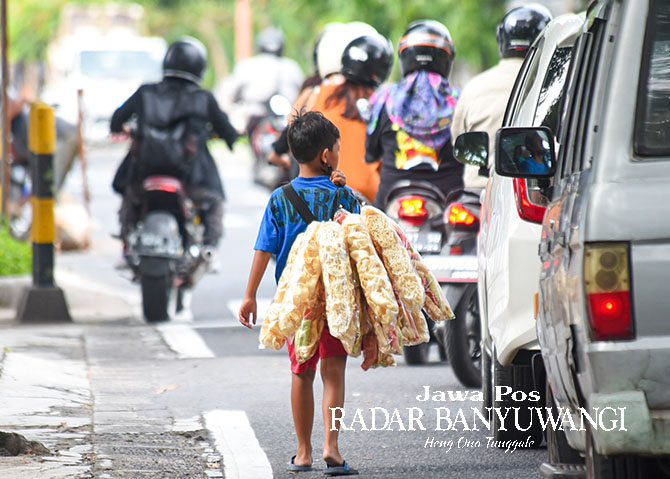 TETAP SEKOLAH: AH, bocah berusia 11 asal Lingkungan Cungking, Kelurahan Mojopanggung, Banyuwangi, menjajakan kerupuk di kawasan traffic light  dekat kantor DPRD Jalan Adi Sucipto Banyuwangi. (Ramada Kusuma/Radar Banyuwangi)