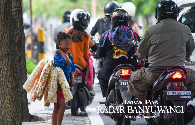 UNTUK BIAYA SEKOLAH: AH berjualan kerupuk di kawasan traffic light  dekat kantor DPRD Jalan Adi Sucipto Banyuwangi. (Ramada Kusuma/Radar Banyuwangi)