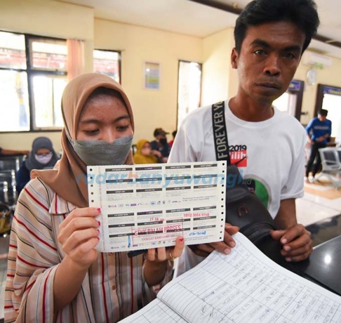 STNK SEMENTARA: Seorang warga yang mengurus layanan di Samsat Banyuwangi menunjukkan surat tanda terima pengganti STNK kemarin (29/3). (Ramada Kusuma/RadarBanyuwangi.id)