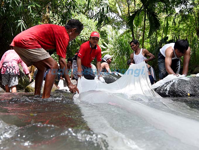 SAMBUT RAMADAN: Warga Cungking, Kelurahan Mojopanggung mencuci kain putih petilasan Buyut Cungking di Sungai Gulung, kemarin (5/3).  (Ramada Kusuma/RadarBanyuwangi.id)
