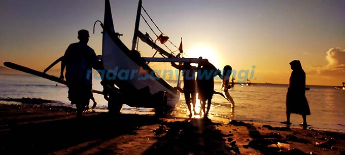 GOTONG ROYONG: Nelayan pantai Blimbingsari memanggul dan mendorong perahu ke tepi pantai usai berlayar, kemarin (12/3). (Deddy Jumhardiyanto/RadarBanyuwangi.id)