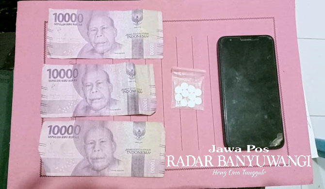 BARANG BUKTI: 30 butir pil koplo, uang Rp 30 ribu, dan HP Oppo biru diamankan di Mapolsek Gambiran. (Rohman untuk Radar Genteng)