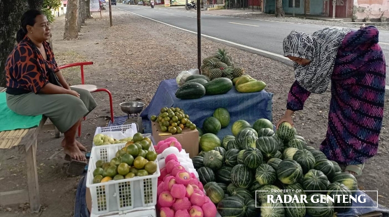 MENUNGGU: Sri Hartatik mulai buka lapak di depan TPU Dusun Krajan, Desa/Kecamatan Cluring, Kamis (23/3). (Foto: Lugas Rumpakaadi/JPRG)