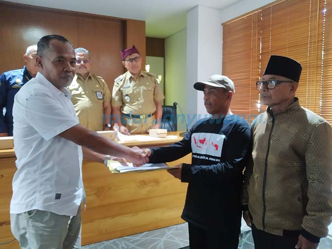 DAMAI: Suto (bertopi) menyerahkan surat pernyataan pengembalian lahan kepada Administratur PT Bumisari Sudjarwo disaksikan Suparmo, perwakilan warga Desa Pakel. (Gareta Wardani/RadarBanyuwangi.id)