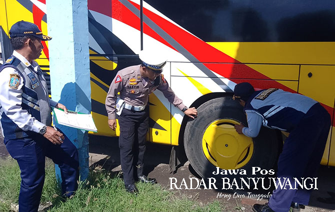 PEMERIKSAAN MENYELURUH: Kanit Kamsel Satlantas Ipda Wahid Hasyim (kanan) bersama petugas Dishub memeriksa kondisi ban bus di Terminal Brawijaya, Kamis (16/3). (Bagus Rio/Radar Banyuwangi)