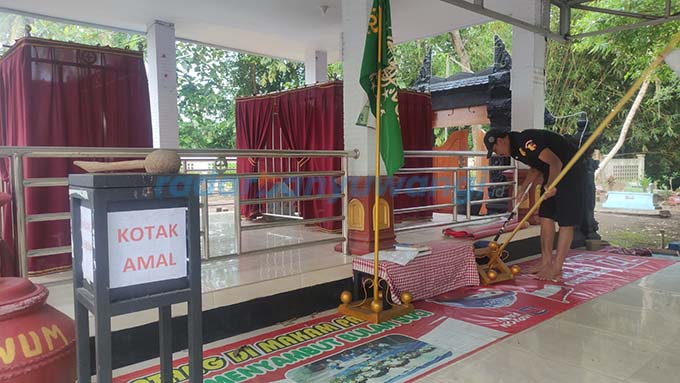 RAWAT MAKAM: Pengurus makam Irawan Suyanto membersihkan makam yang dipercaya pesarean Prabu Tawang Alun di Dusun Sukodadi, Desa Sraten, Kecamatan Cluring, kemarin (10/4). (Lugas Rumpaakadi/RadarBanyuwangi.id)