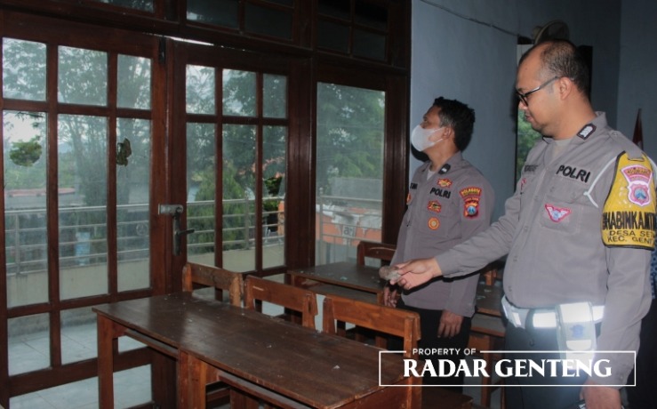 RUSAK: Anggota Polsek Genteng melihat kaca jendela gedung PSCM Genteng yang rusak karena dilempari batu, Selasa (4/4). (Foto: Salis Ali/JPRG)