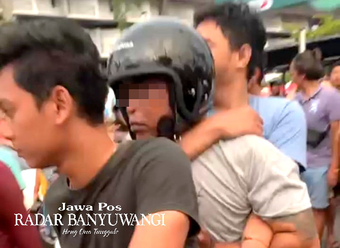 DINAIKKAN MOTOR: Anggota Resmob membawa NS (tengah) ke Polresta Banyuwangi sesaat setelah pria asal Singojuruh tersebut tertangkap tangan mencuri motor di Pasar Takjil Sobo, Jumat lalu (31/3).  (Tangkapan Layar Video Netizen)