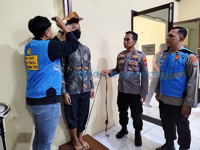 TES TINGGI BADAN: Calon siswa anggota Polri melaksanakan pengukuran tinggi badan di Polresta Banyuwangi, Rabu (12/4). Petugas menyeleksi data pendaftar casis Polri. (Bagus Rio/Radar Banyuwangi)