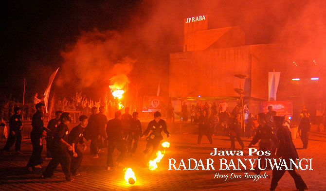 ATRAKSI: Para pendekar pencak silat Pagar Nusa bermain bola api pada malam hari di lapangan parkir Grha Pena Banyuwangi beberapa waktu lalu. (Ramada Kusuma/Radar Banyuwangi)