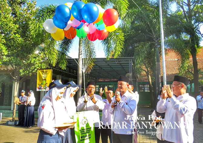 JADI PELOPOR: Kepala Kantor Kemenag Banyuwangi Moh. Amak Burhanudin (pegang mikrofon) menyaksikan pelepasan balon harapan sebagai simbol Penerapan 18 Nilai Pendidikan Karakter di MTsN 12 Banyuwangi, Selasa (23/5). (Saiful Umar untuk Radar Banyuwangi)