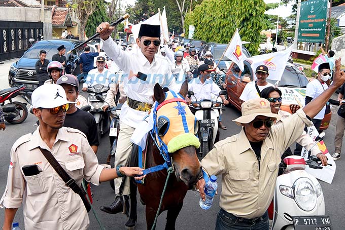 MENUNGGANG KUDA: Ketua DPC Gerindra Banyuwangi Naufal Badri diiringi ratusan kader dan simpatisan mendaftarkan bacalegnya ke kantor KPU, Sabtu kemarin (13/5). (Ramada Kusuma/RadarBanyuwangi.id)