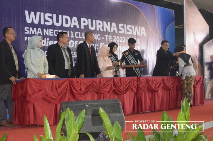 PROSESI: Kepala SMAN 1 Cluring Imam Nursamsudin mengalungkan gordon didampingi para wakil kepala sekolah dalam wisuda di Hotel New Surya, Kecamatan Gambiran Kamis (4/5). (Foto: Thomy Sila /JPRG)