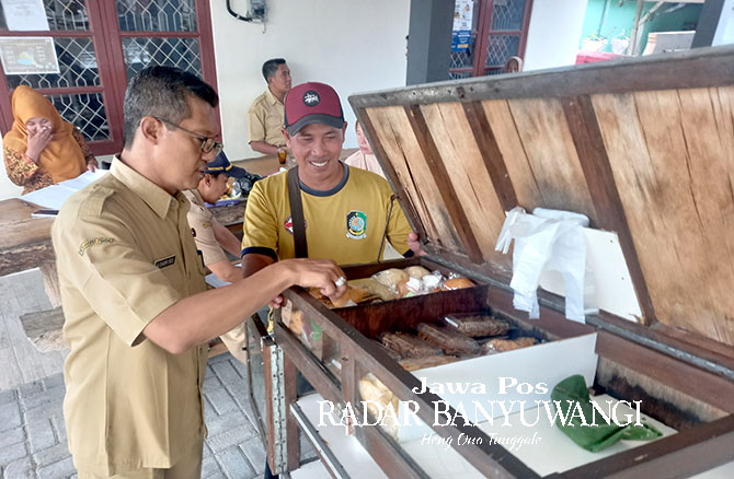 USAHA MASYARAKAT : Chaidir Sidqi menjajal jajanan rakyat yang dijajakan secara keliling pada Selasa (16/5). (Ayu Lestari /Radar Banyuwangi)