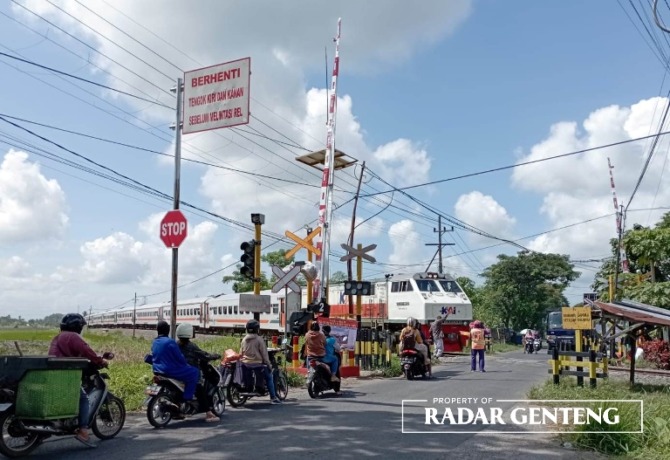 JAGA PERJALANAN: Palang pintu di lintasan KA Dusun Tegalmojo, Desa Gumirih, Kecamatan Singojuruh yang masih baru belum berfungsi, relawan masih jaga untuk pengamanan, Senin (8/5). (Foto: Lugas Rumpakaadi/JPRG)