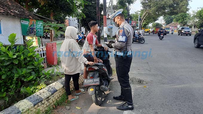 TAK PAKAI HELM: &nbsp;Anggota Satlantas Polresta Banyuwangi menindak pelanggar lalin di dekat traffic light Mojopanggung, Jumat kemarin (19/5). (Bagus Rio/RadarBanyuwangi.id)