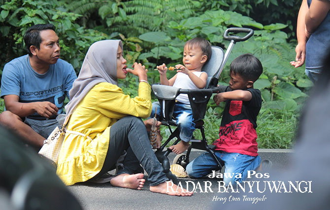 SANTAI: Keluarga yang terjebak macet memilih turun dari mobilnya makan cilok dengan klesotan di jalan aspal di Jalur Gumitir, Jumat (19/5) (Salis Ali/Radar Genteng)
