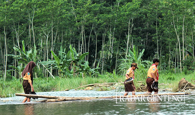 SEMANGAT: Para siswa SDN 2 Kandangan dari Afdeling Paal Empat dan Afdeling Paal Enam, Desa Kandangan, Kecamatan Pesanggaran pulang dari sekolah dengan menyeberangi sungai, Jumat (12/5). (Salis Ali/Radar Genteng)
