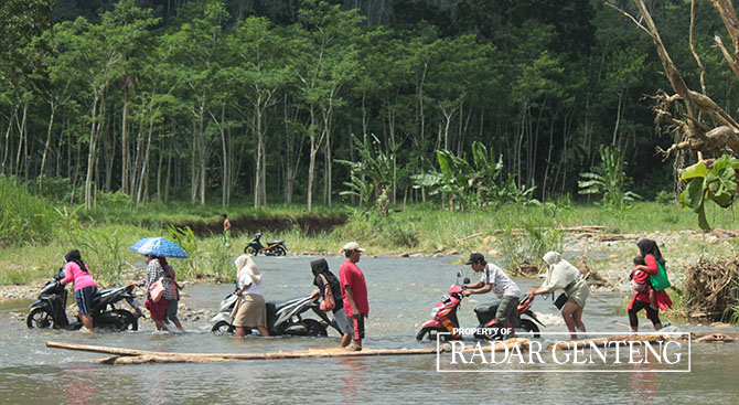 SUSAH PAYAH: Warga harus mendorong motornya untuk menyeberangi Sungai Karangtambak menuju Afdeling Paal Empat dan Afdeling Paal Enam, Dusun Sumberjambe, Desa Kandangan, Kecamatan Pesanggaran, Jumat (12/5). (Salis Ali/Radar Genteng)