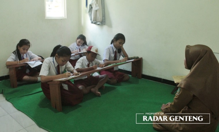 KONSENTRASI: Para siswa kelas VI SDN 7 Tegalharjo, Kecamatan Glenmore melaksanakan UAS dengan lesehan di gedung TPQ Desa Karangharjo, Kecamatan Glenmore, Senin (15/5). (Foto: Salis Ali/JPRG)