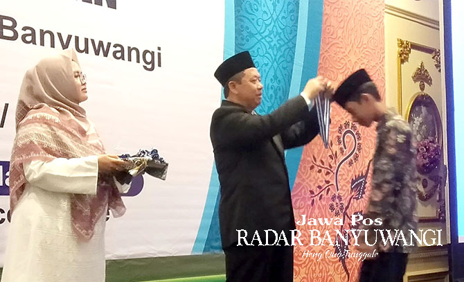 MOMEN SAKRAL: Ketua Yayasan Al Uswah Karyono mewisuda siswa-siswi SDIT Al Uswah Kalipuro pada acara perpisahan dan apresiasi Alquran di hall Aston Hotel Banyuwangi pada Minggu (4/6). (Toha/Radar Banyuwangi)