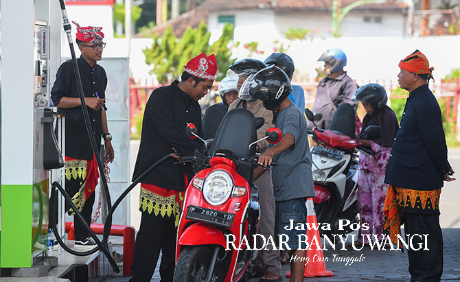 PAKAI UDENG: Petugas SPBU Karangente, Jalan Brawijaya, Banyuwangi, melayani pembeli dengan memakai pakaian adat khas Oseng. (Ramada Kusuma/Radar Banyuwangi)